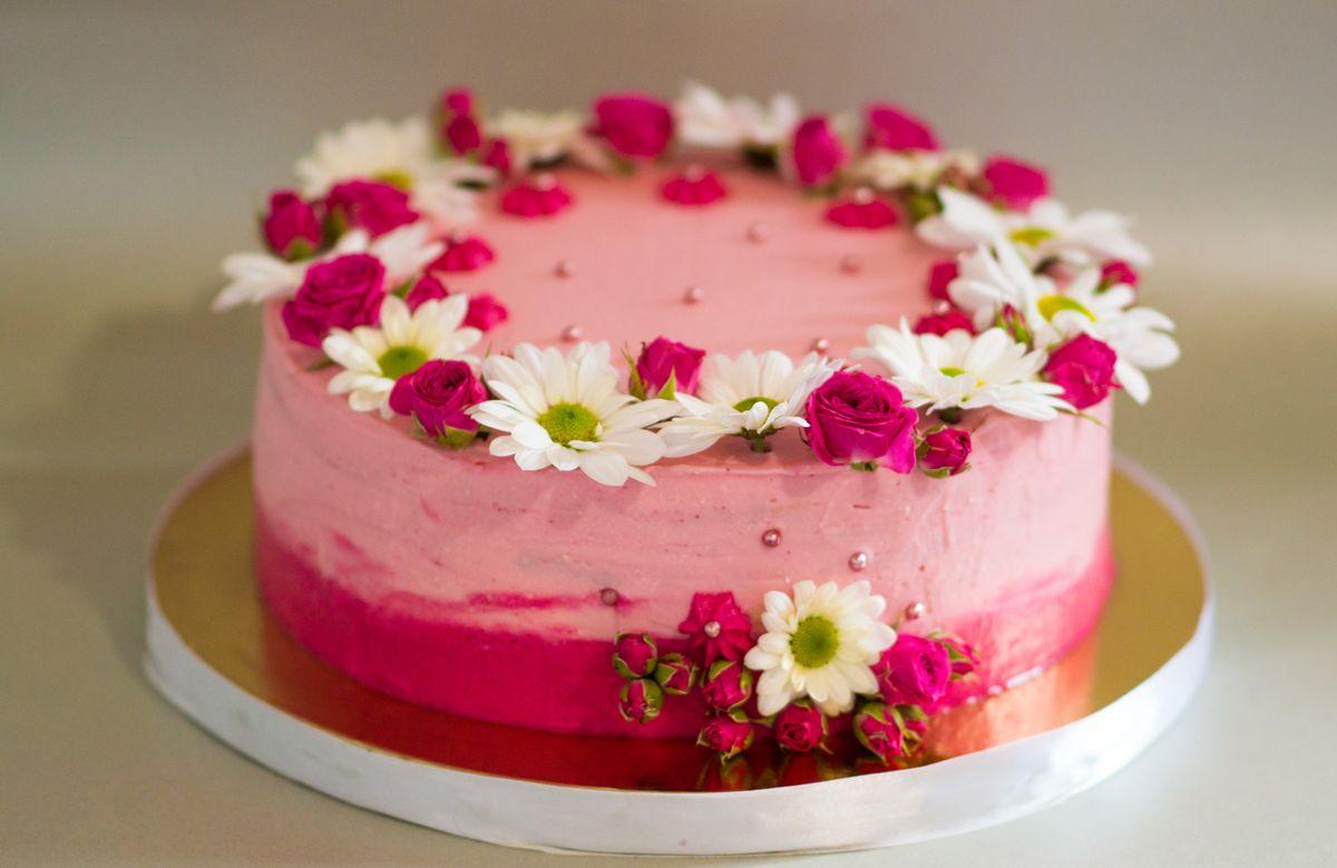 
Honey cake with fruit filling and pink icing, beautiful flowers and edible silver as decoration. Pink cake decorated with live roses and chrysanthemums